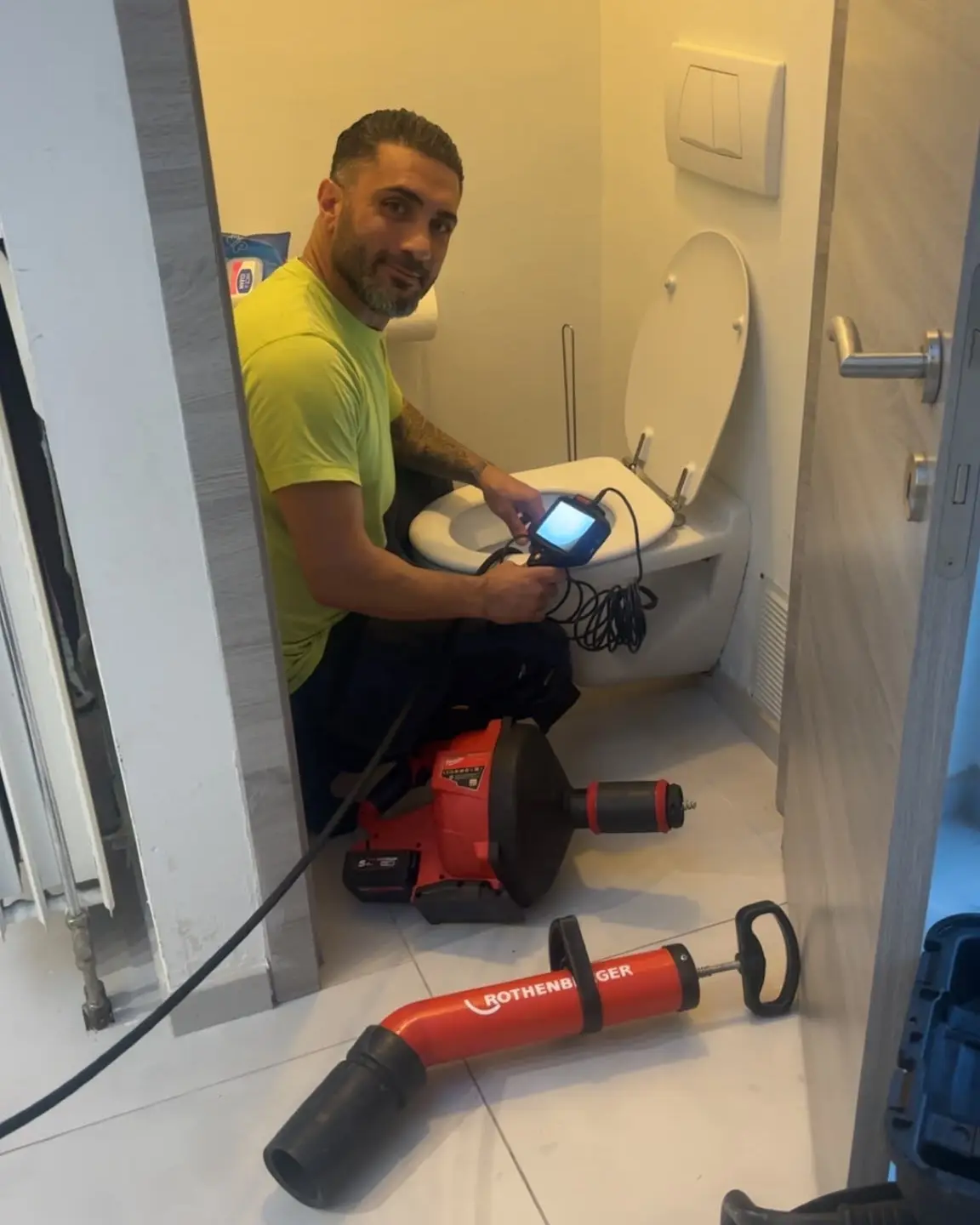 Murat, déboucheur HelpDrain, contrôle un WC à la caméra d'inspection dans un appartement bruxellois, machine à tambour au sol