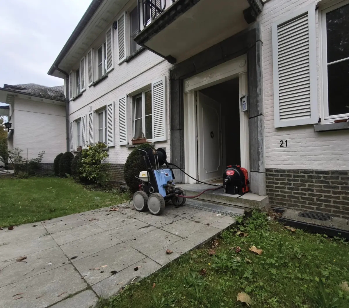 Hydrocureur haute pression et machine de curage devant la porte d'une grande maison à Uccle, chantier HelpDrain