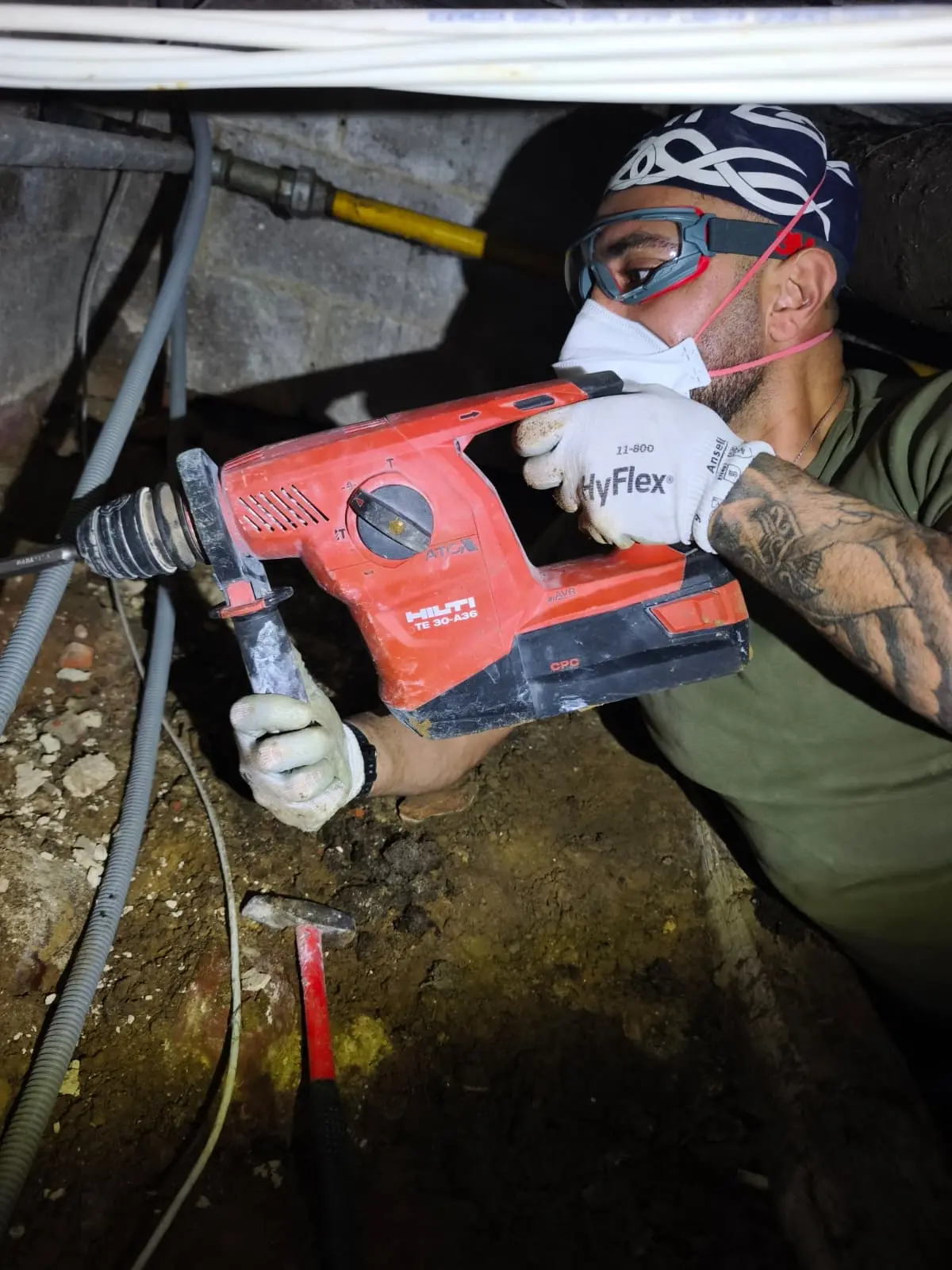 Technicien HelpDrain au perforateur dans le vide sanitaire, pose de la nouvelle évacuation à Uccle