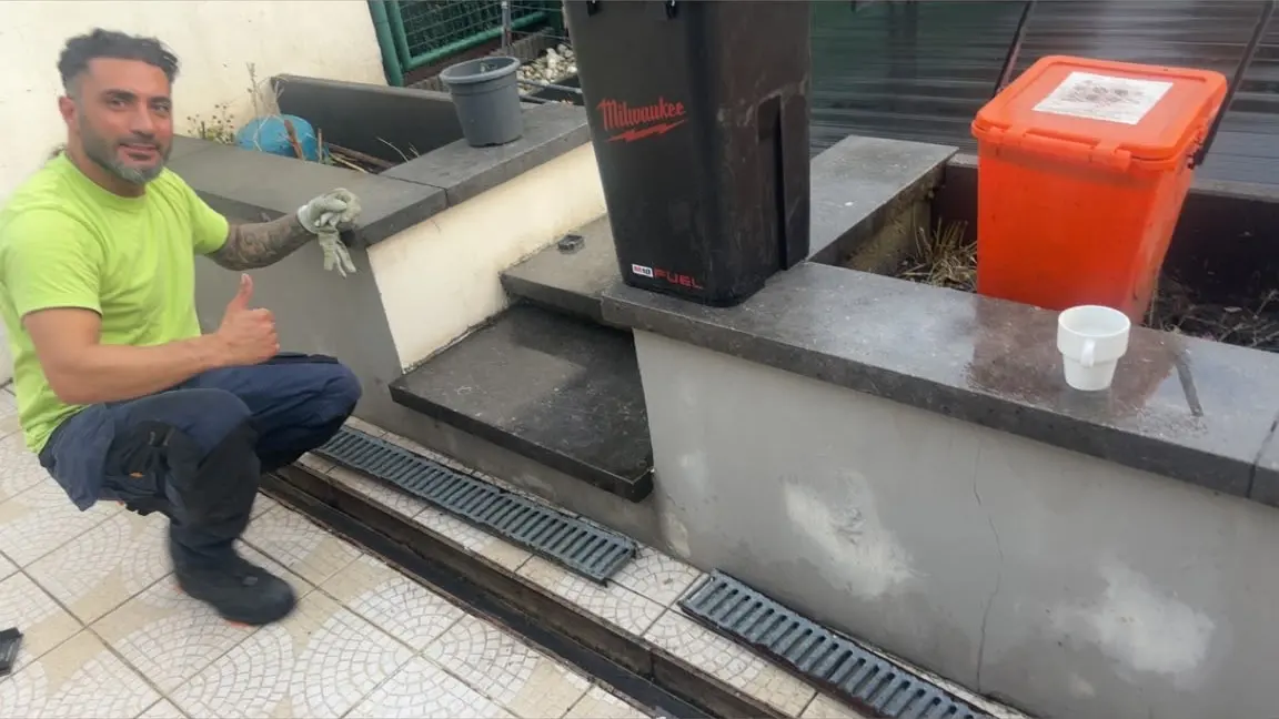 Technicien HelpDrain accroupi près du caniveau d'une cour à Bruxelles après une intervention de débouchage
